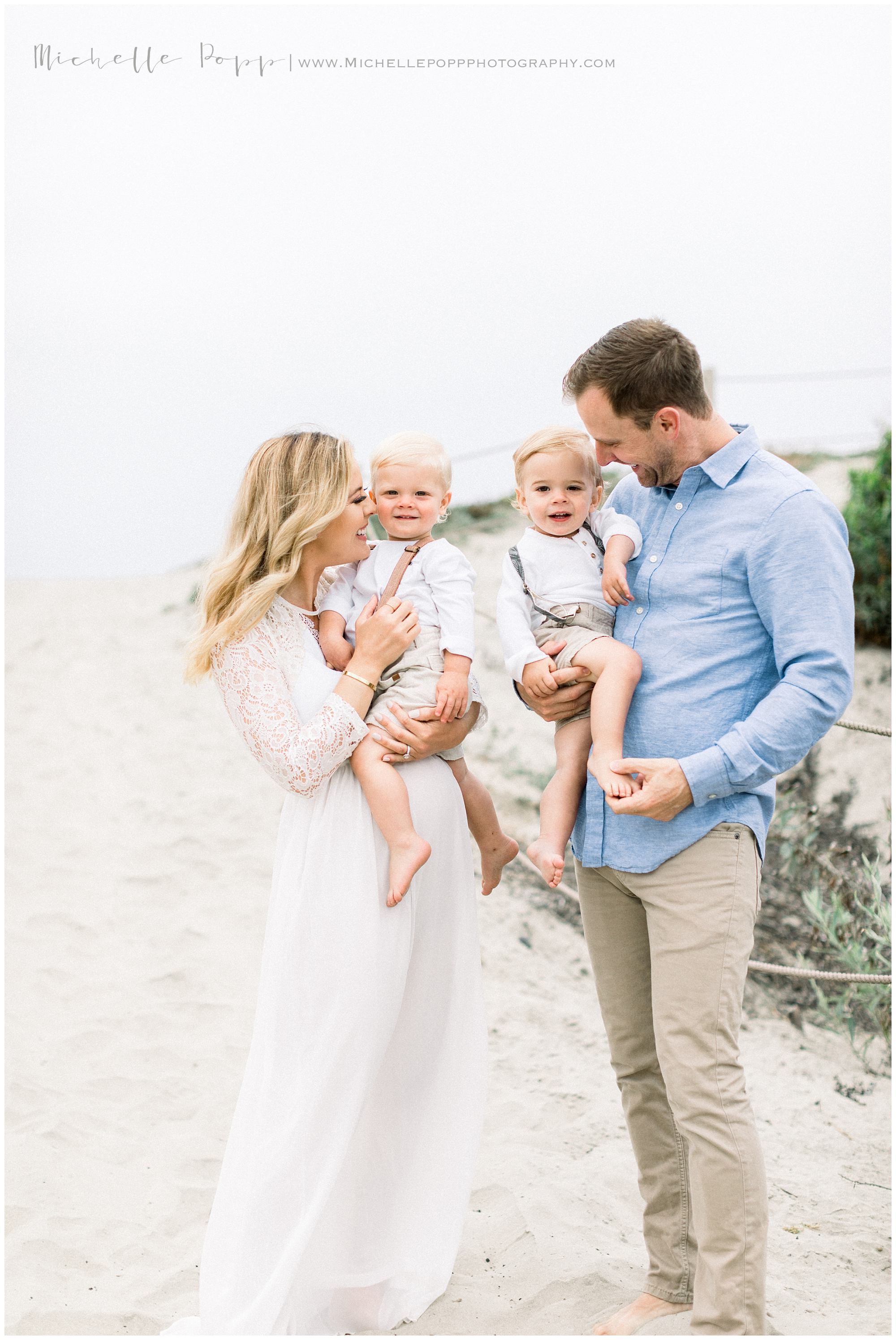 mom and dad holding boys on the beach