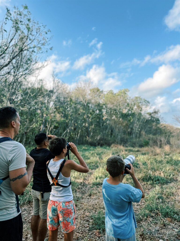 boy taking photos and looking at parrots through binoculars on Sloth & Monkey Tour at Morgan Rock's Nicaragua
