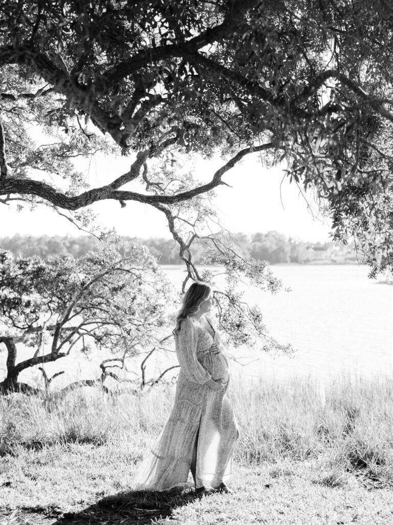 pregnant mom standing near water in Topsail holding belly