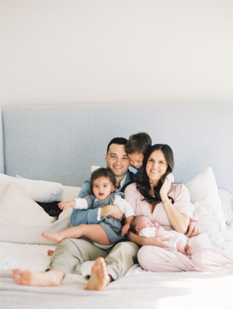 family snuggled in before with newborn baby in home lifestyle newborn photography